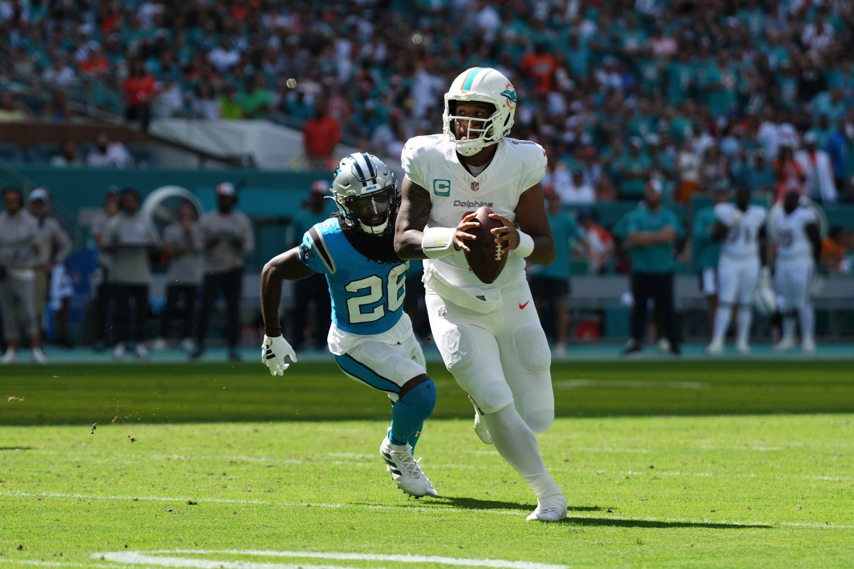 Tua Tagovailoa runs with the ball in two hands as a Panthers player chases him